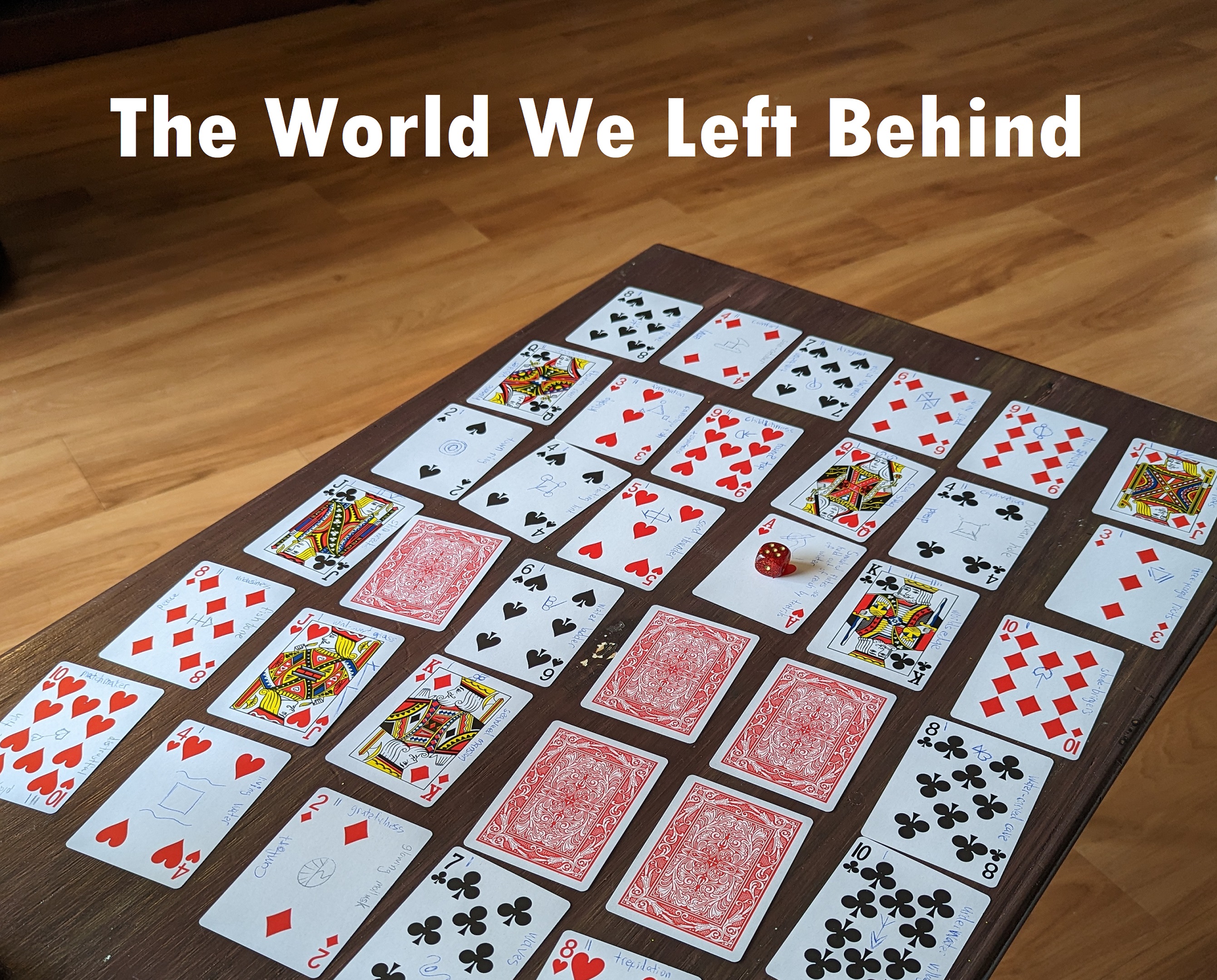 The temporary cover art of The World We Left Behind. It shows a table with a 6x6 grid of playing cards. Most of the cards are face-up, but a few are still face-down. The cards have drawings and writing on them.